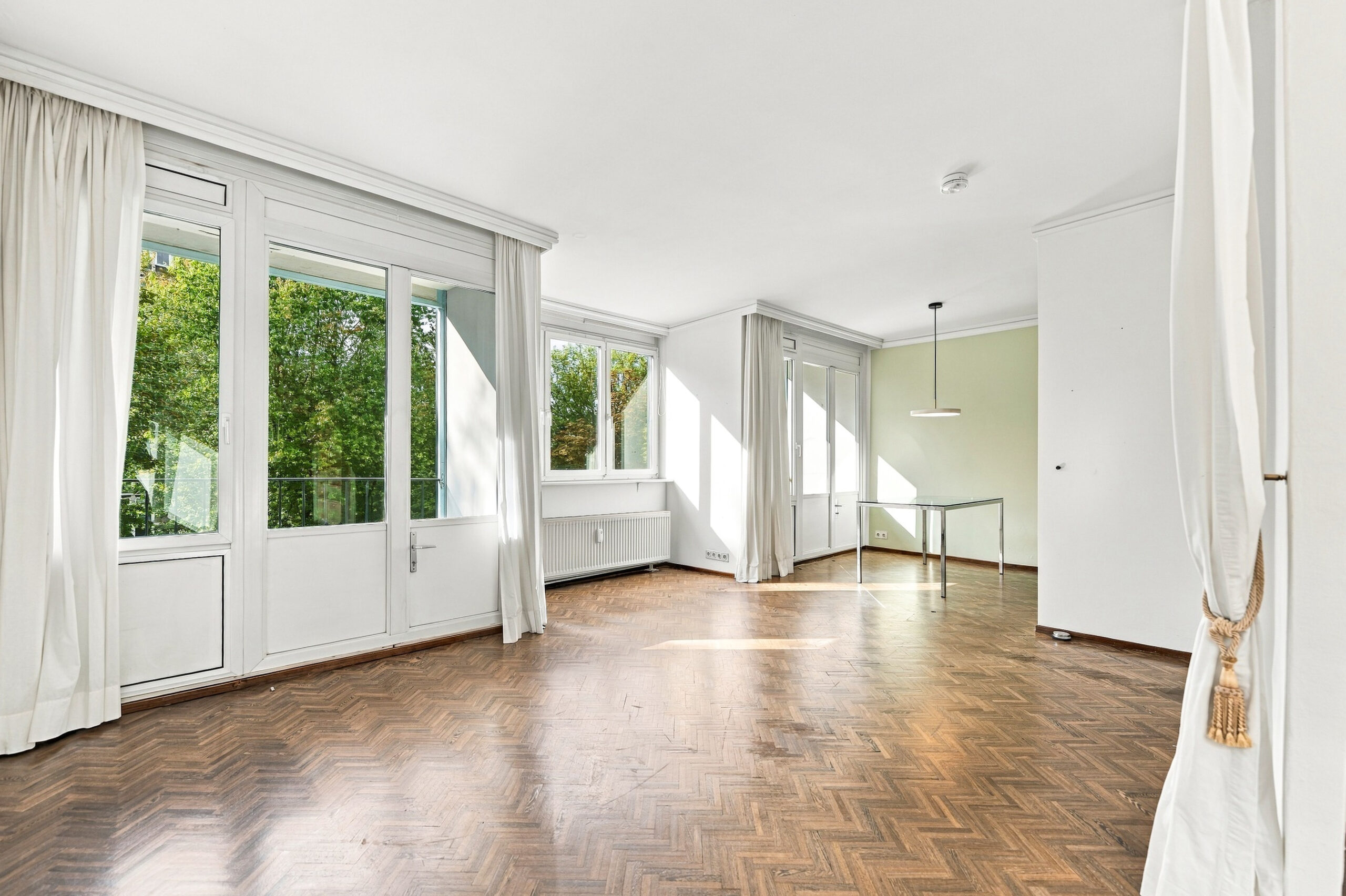 Spacious living room with multiple windows and curtains