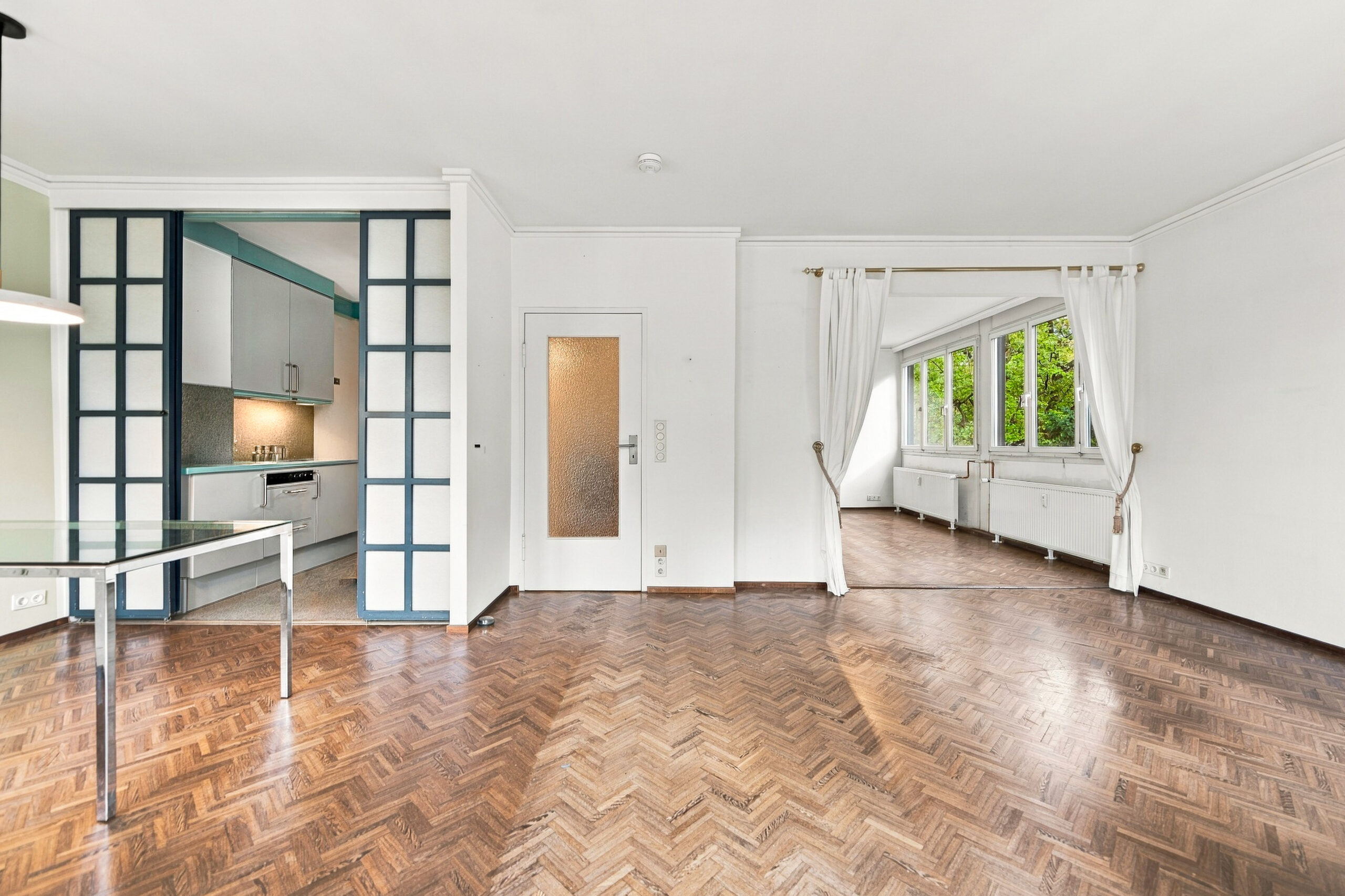 Open living space with parquet floor and glass door