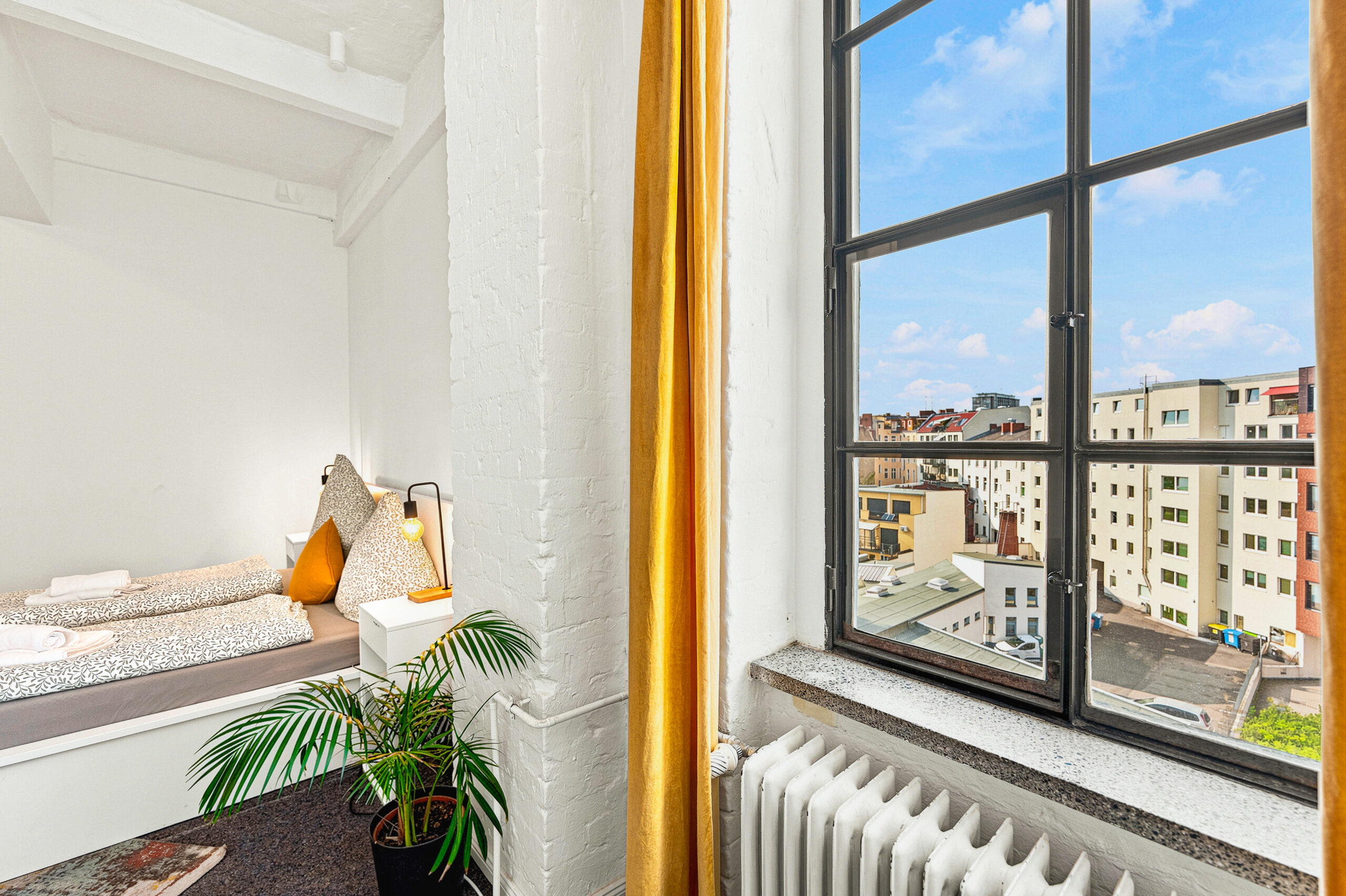 Cozy bedroom corner with built-in bed, plant, and city view