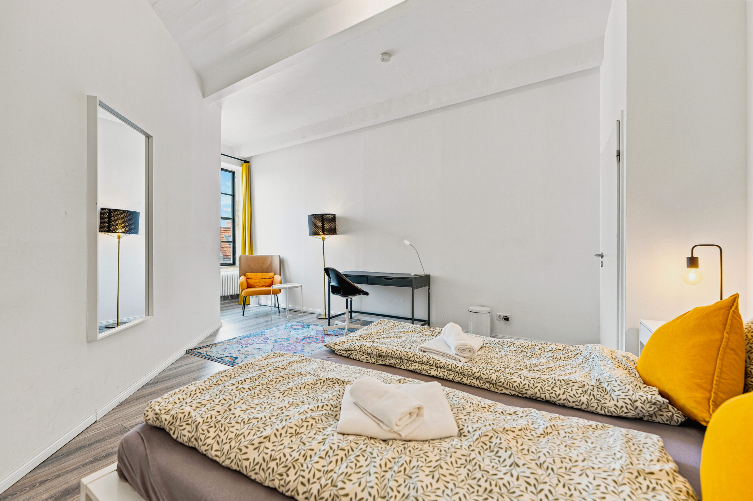 Contemporary bedroom with beige bed, yellow accents, and sloped ceiling