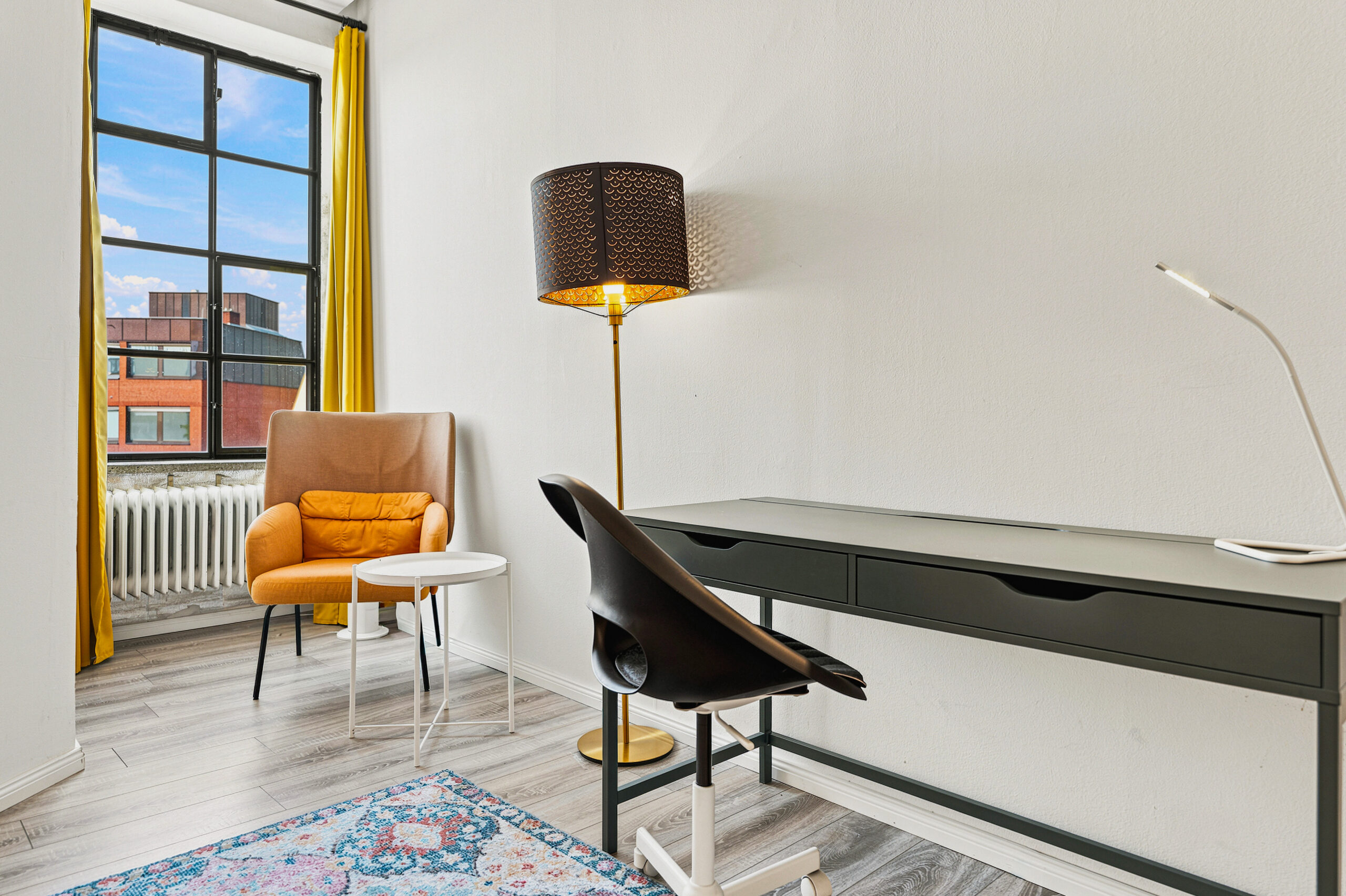Bedroom with workspace, yellow-framed window, orange chair, and piano
