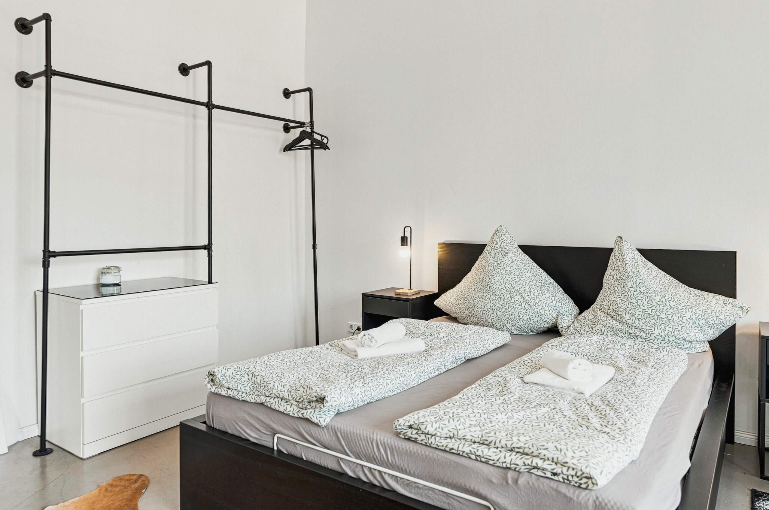 Close-up of black bed frame with white and patterned bedding