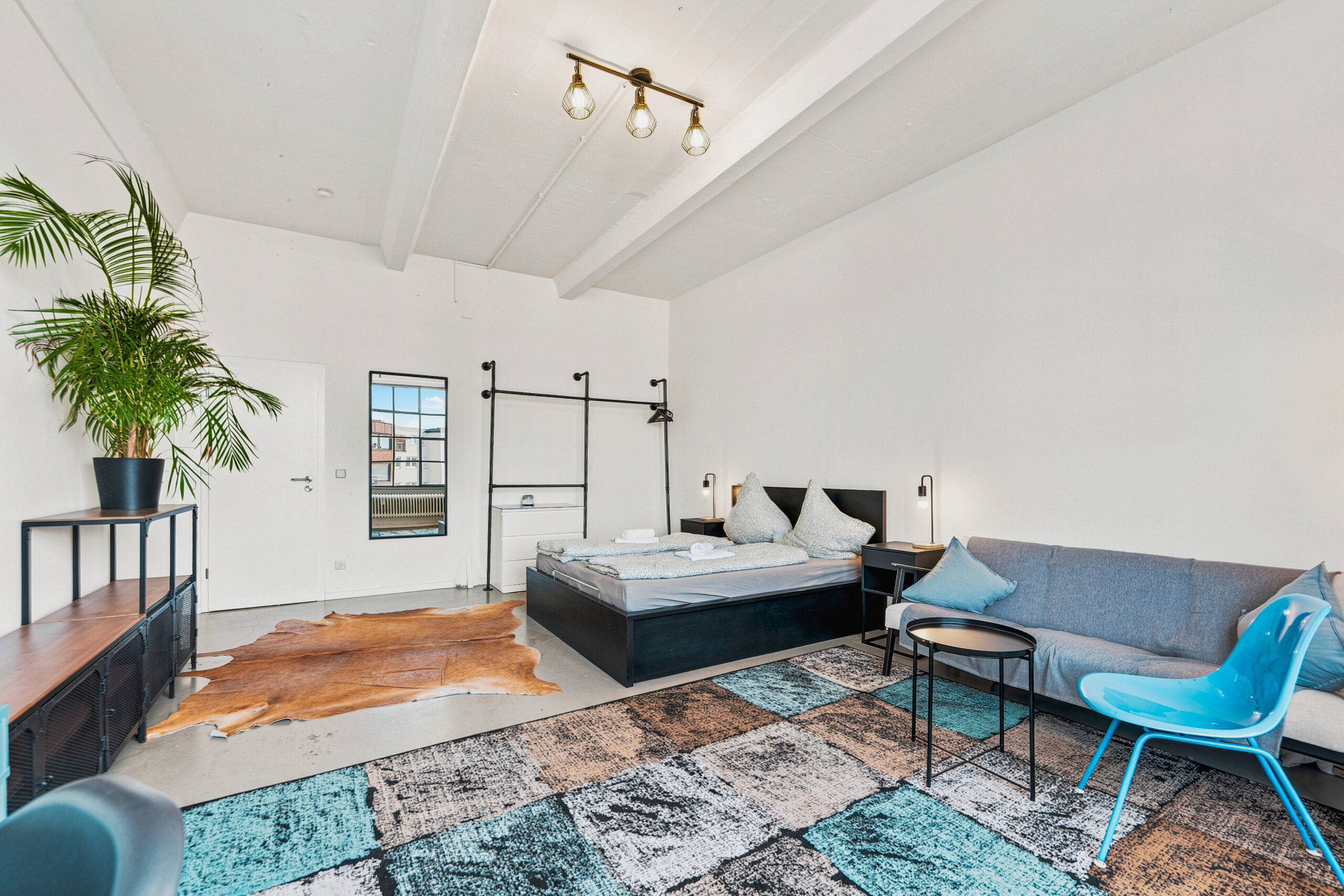 Spacious bedroom with black bed frame and blue accent chair