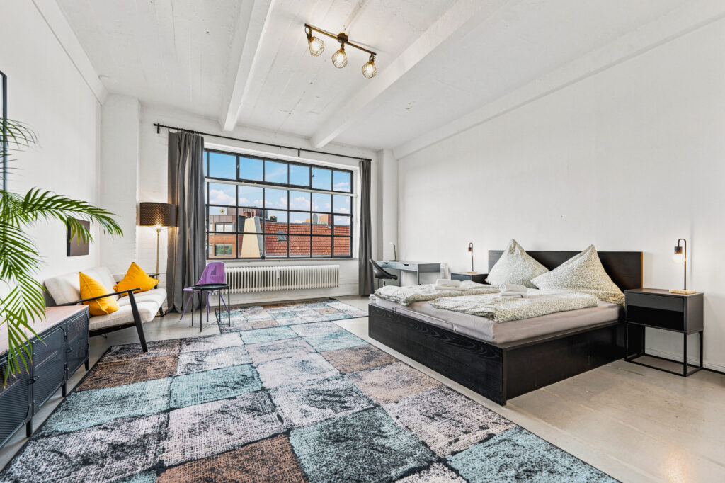 Spacious loft bedroom with window seating and industrial architecture