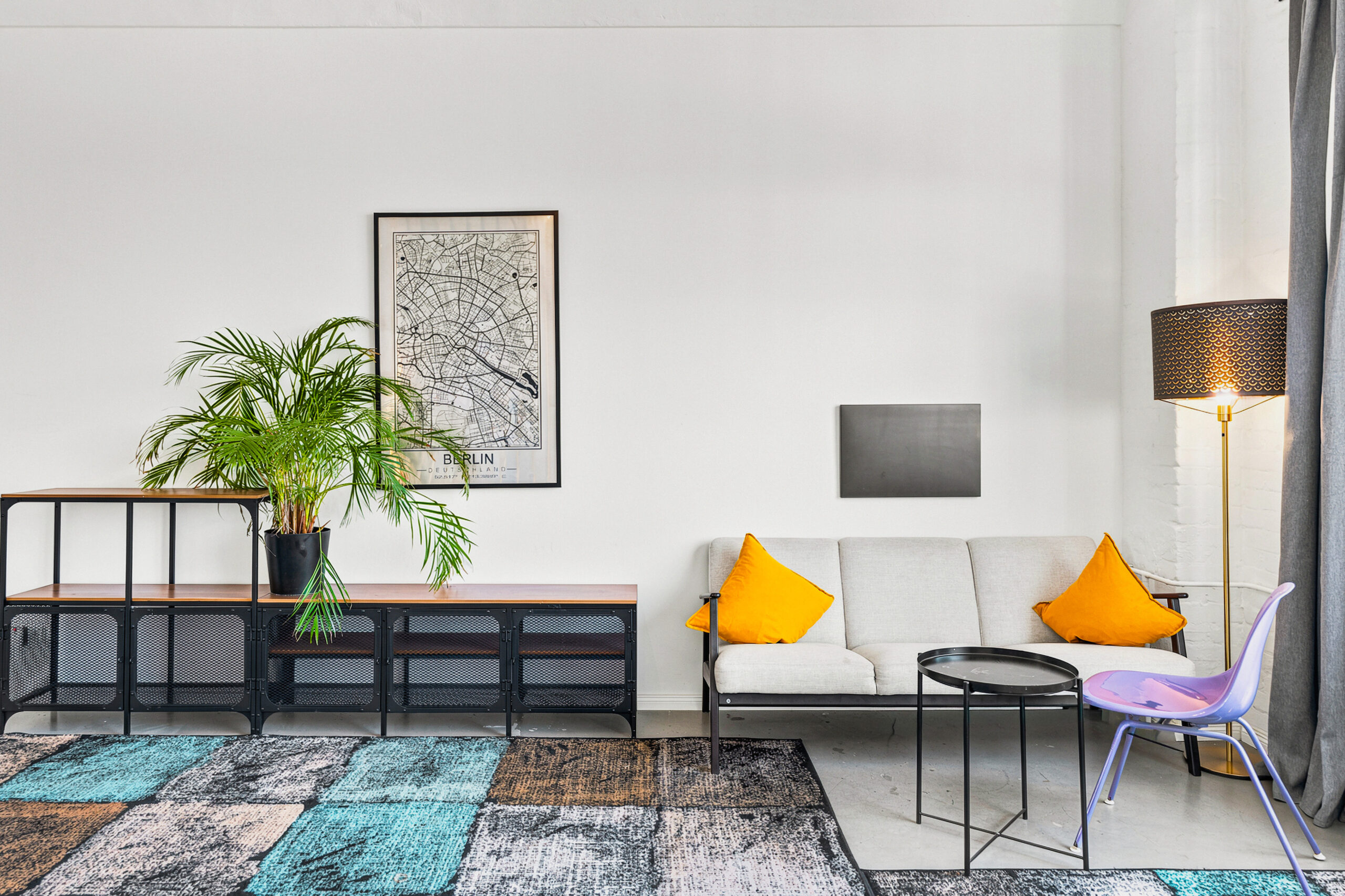 Living room with sofa, colorful pillows, and industrial shelving