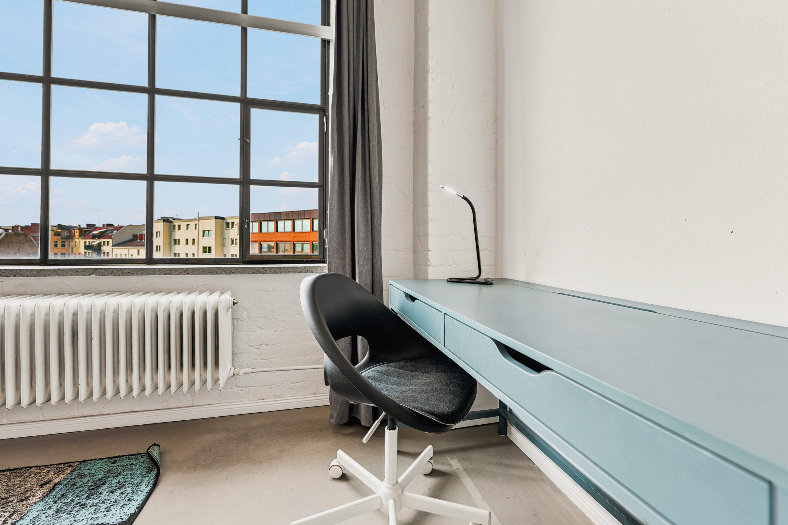 Minimalist desk workspace with large industrial window and city view