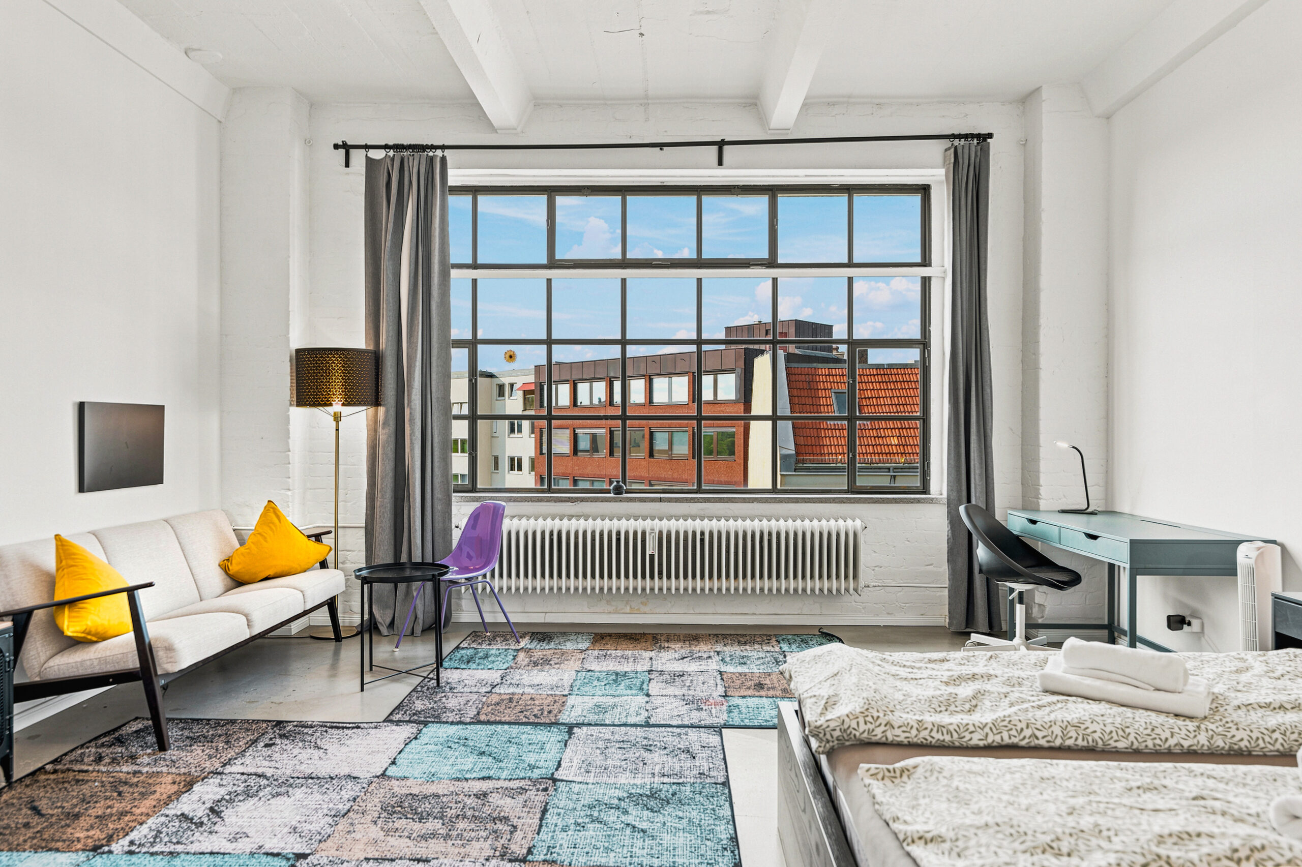 Airy bedroom with large grid windows, yellow accents, and lounge