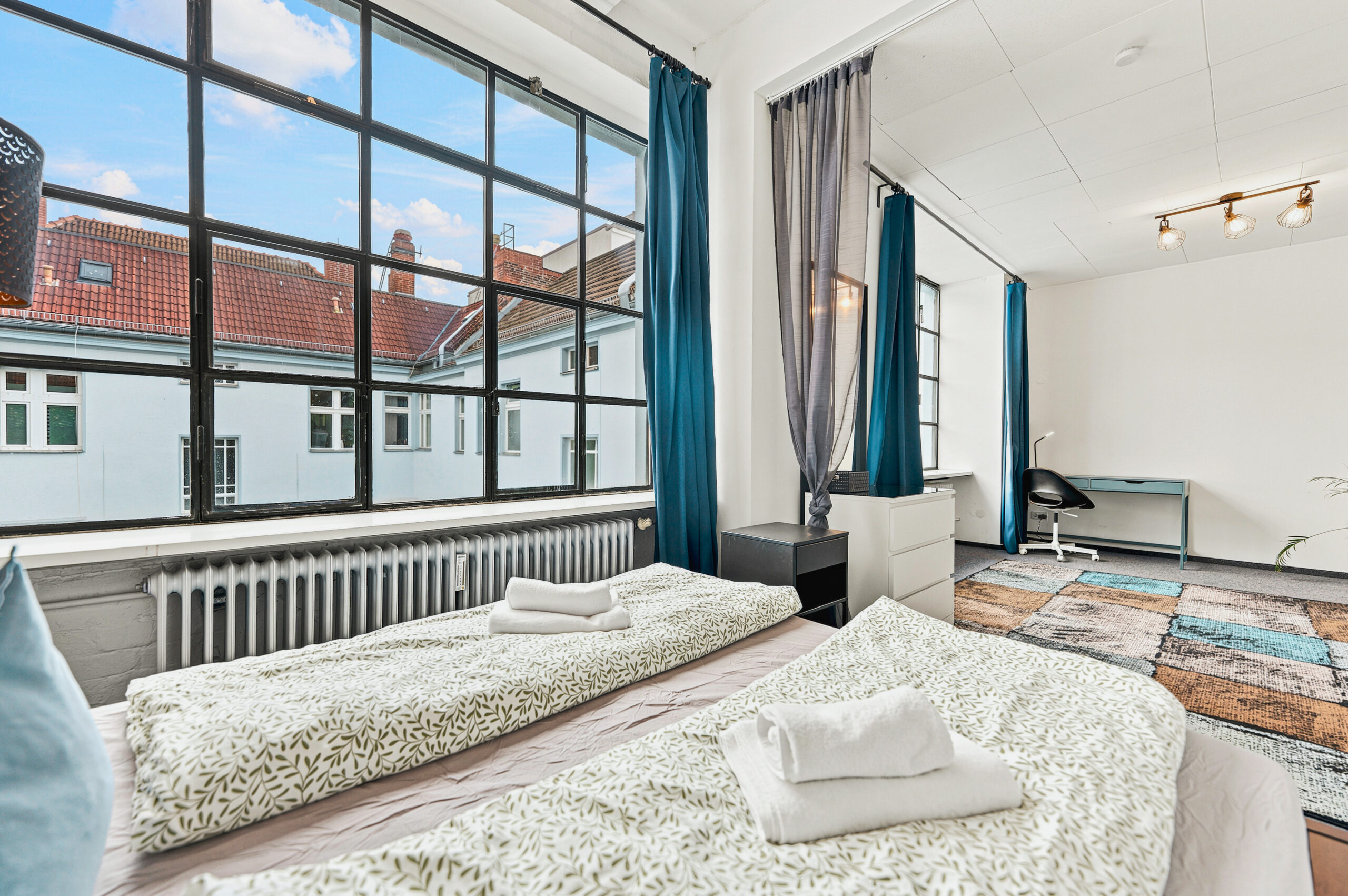 Modern bedroom with oversized industrial windows and city views