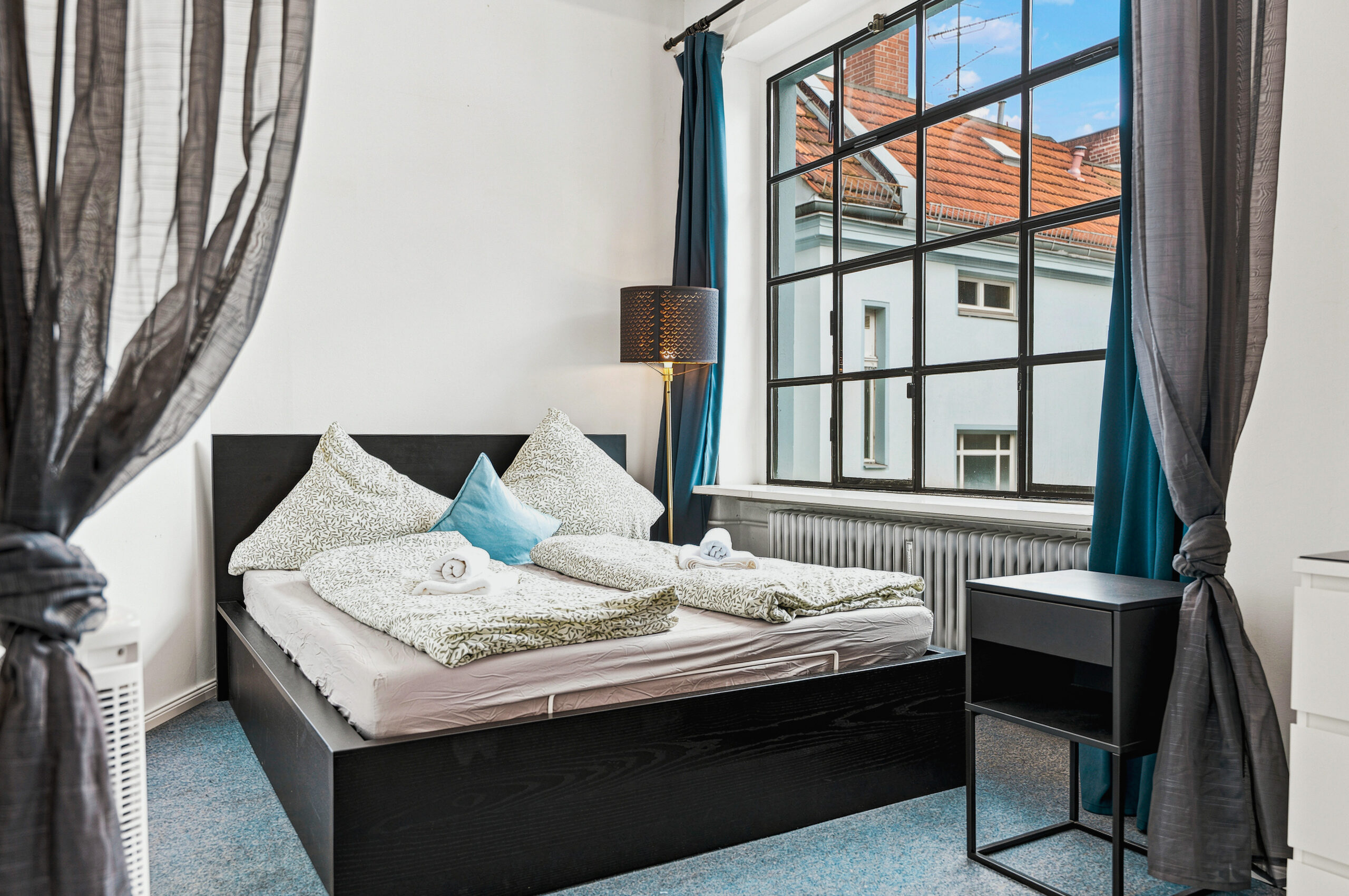 Cozy bedroom with black bed frame and industrial window