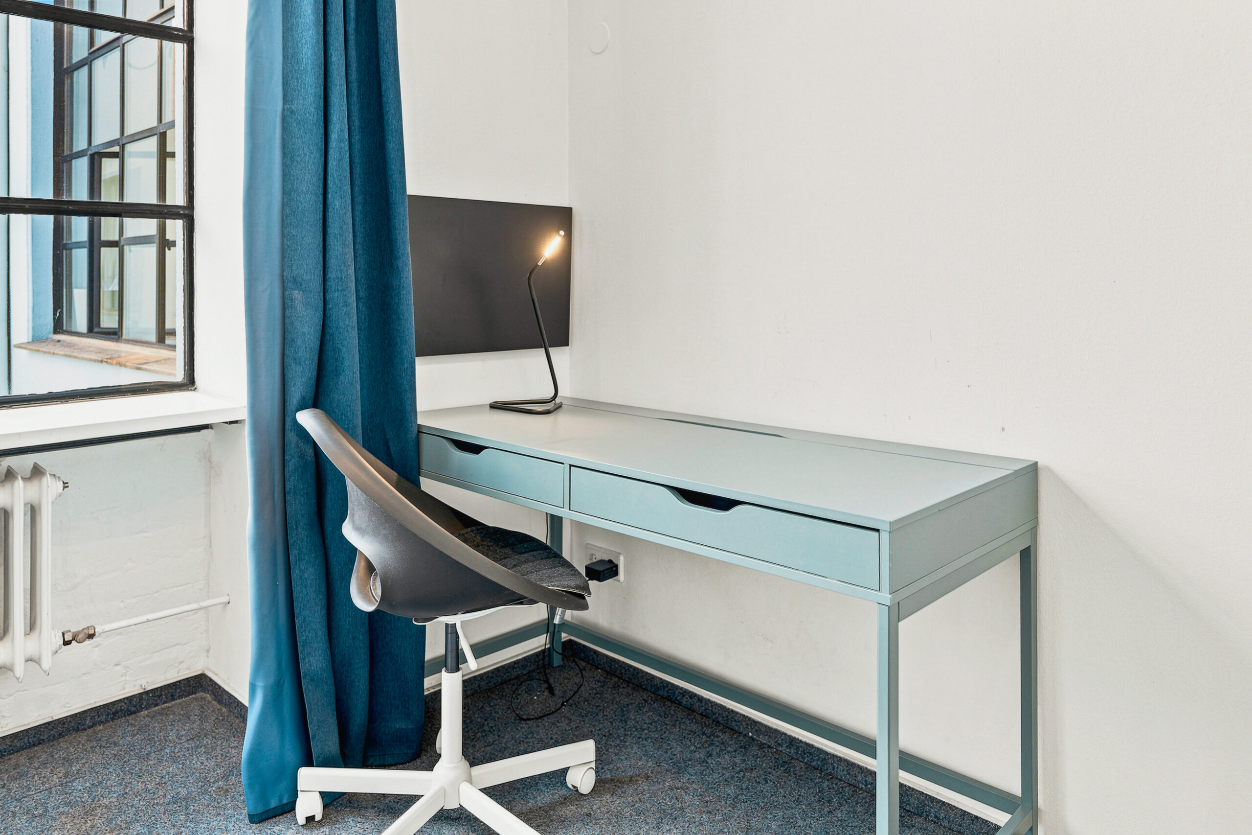 Minimalist bedroom workspace with turquoise desk and chair