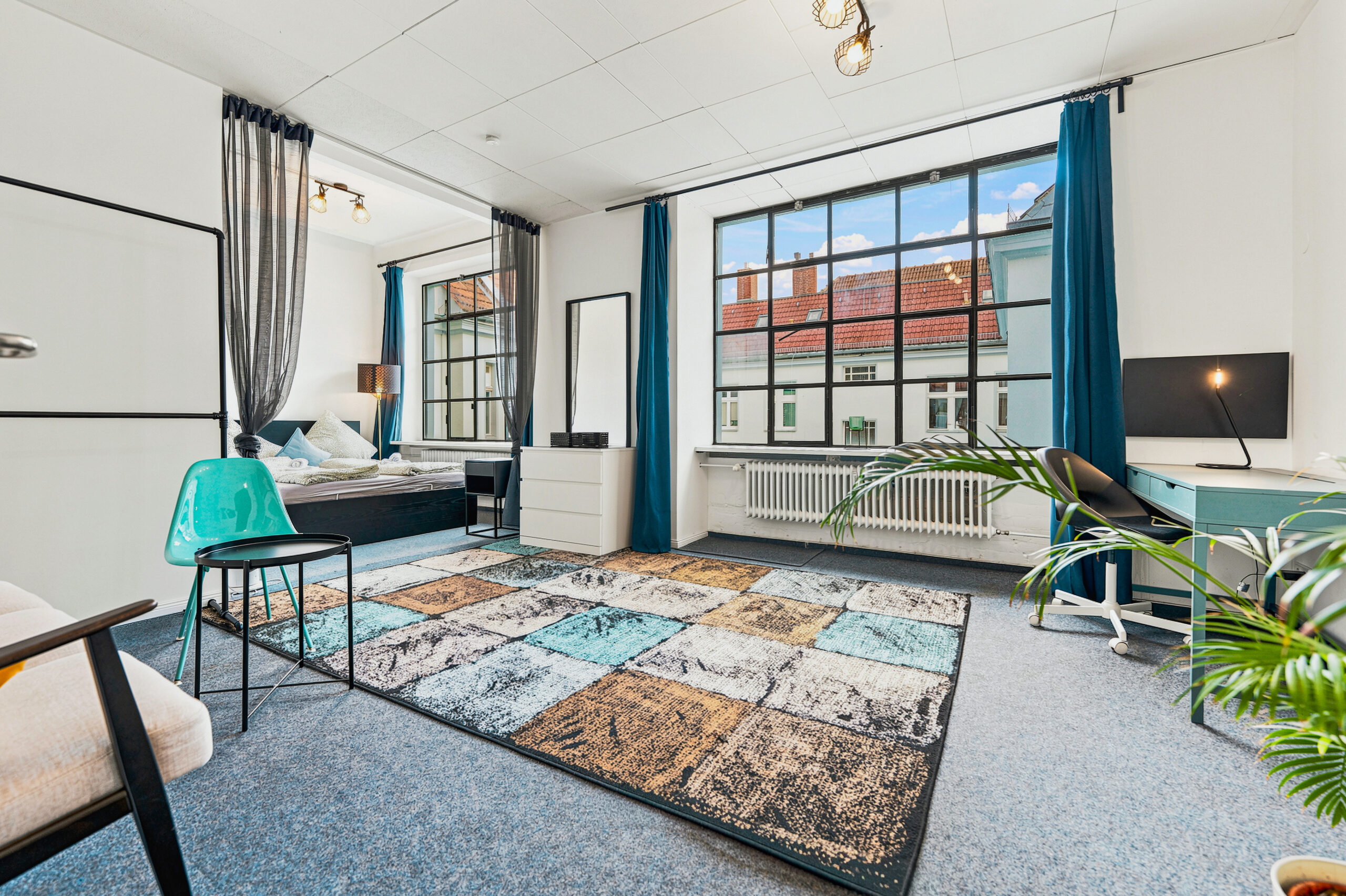 Spacious loft bedroom with large windows and turquoise accents