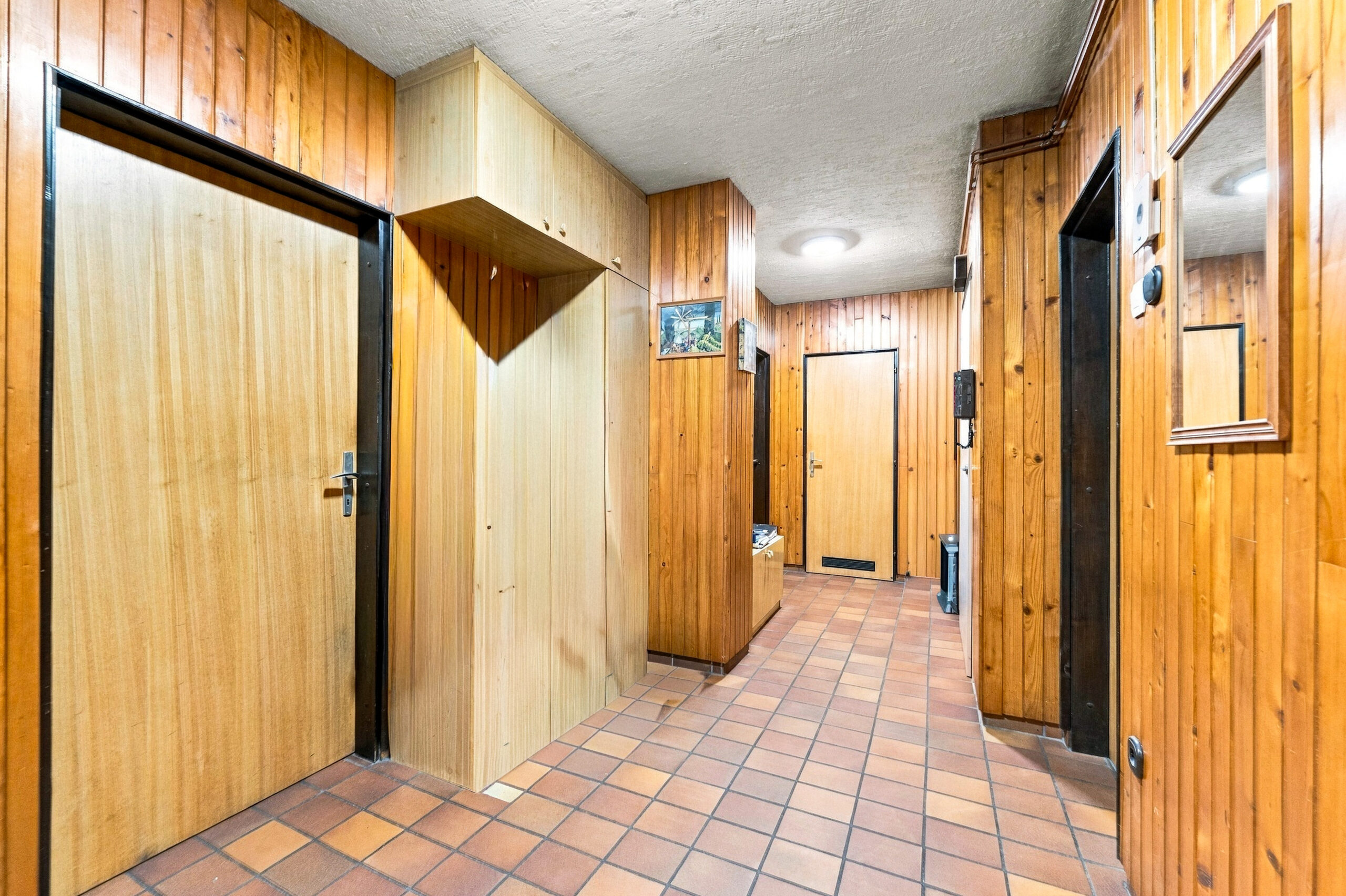 Wood-paneled hallway with tiled floor and doors