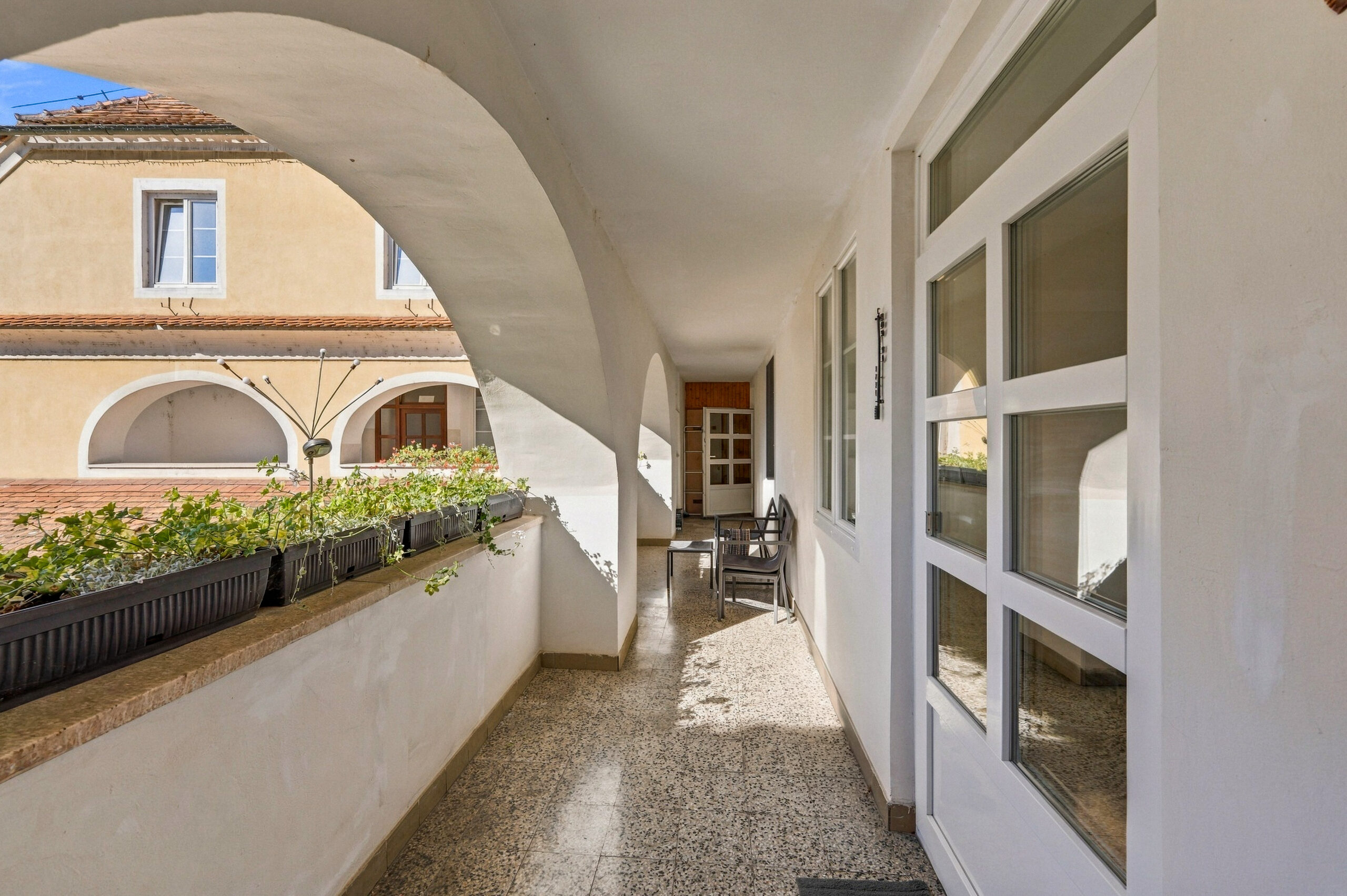 Arched terrace corridor with plants and doorway