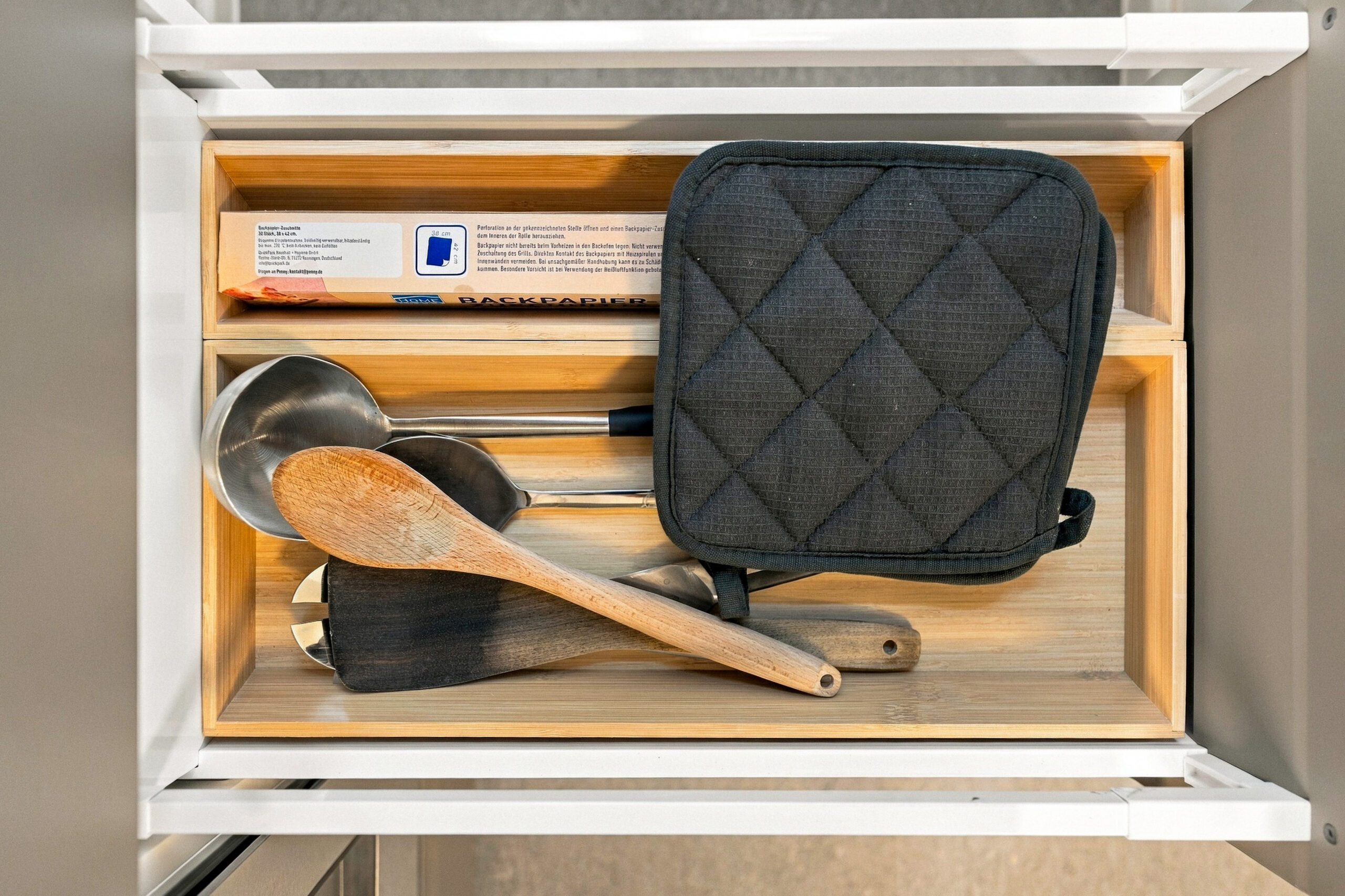 Open drawer with kitchen utensils and pot holder
