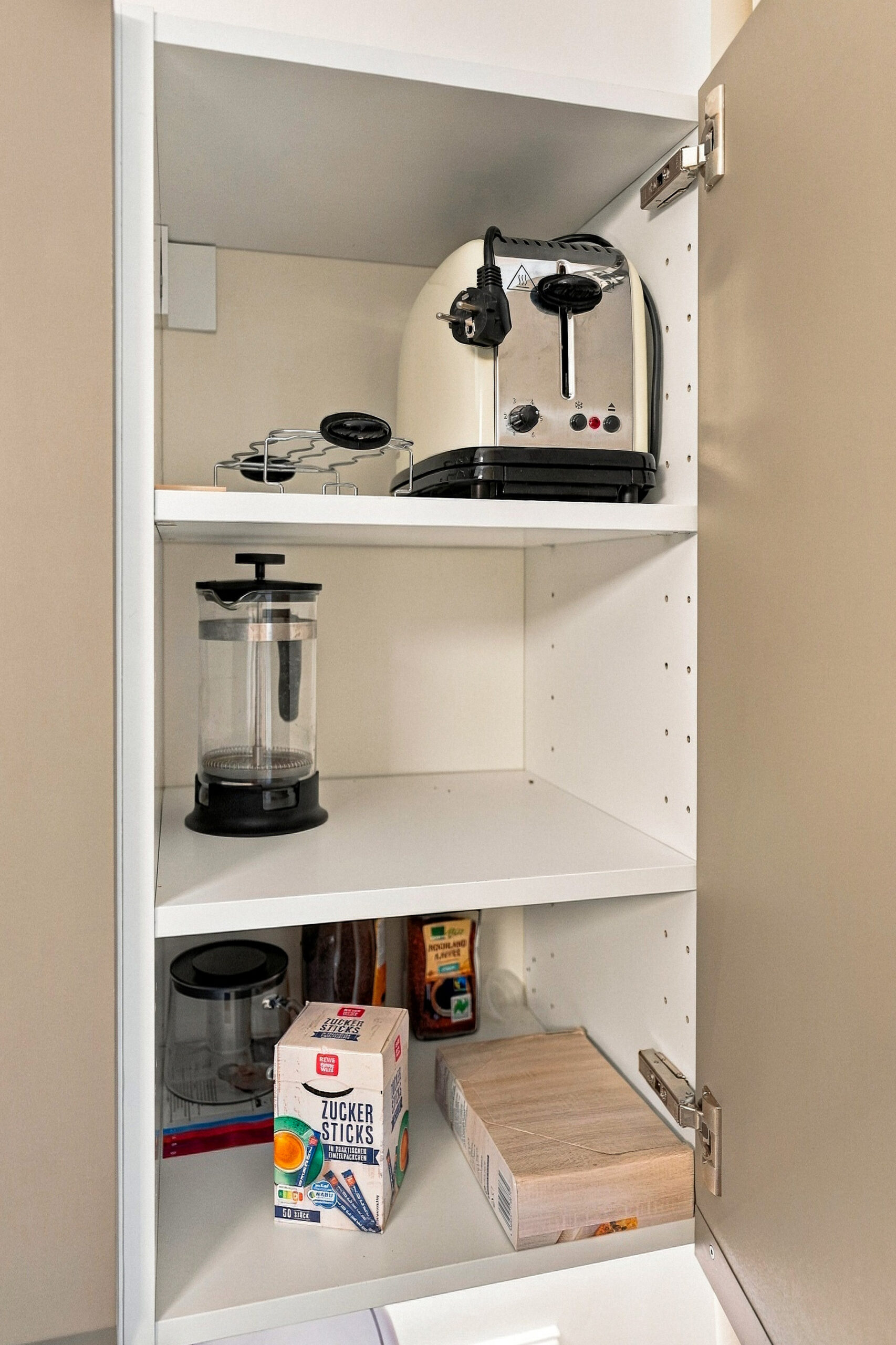 Open cabinet with coffee maker and supplies
