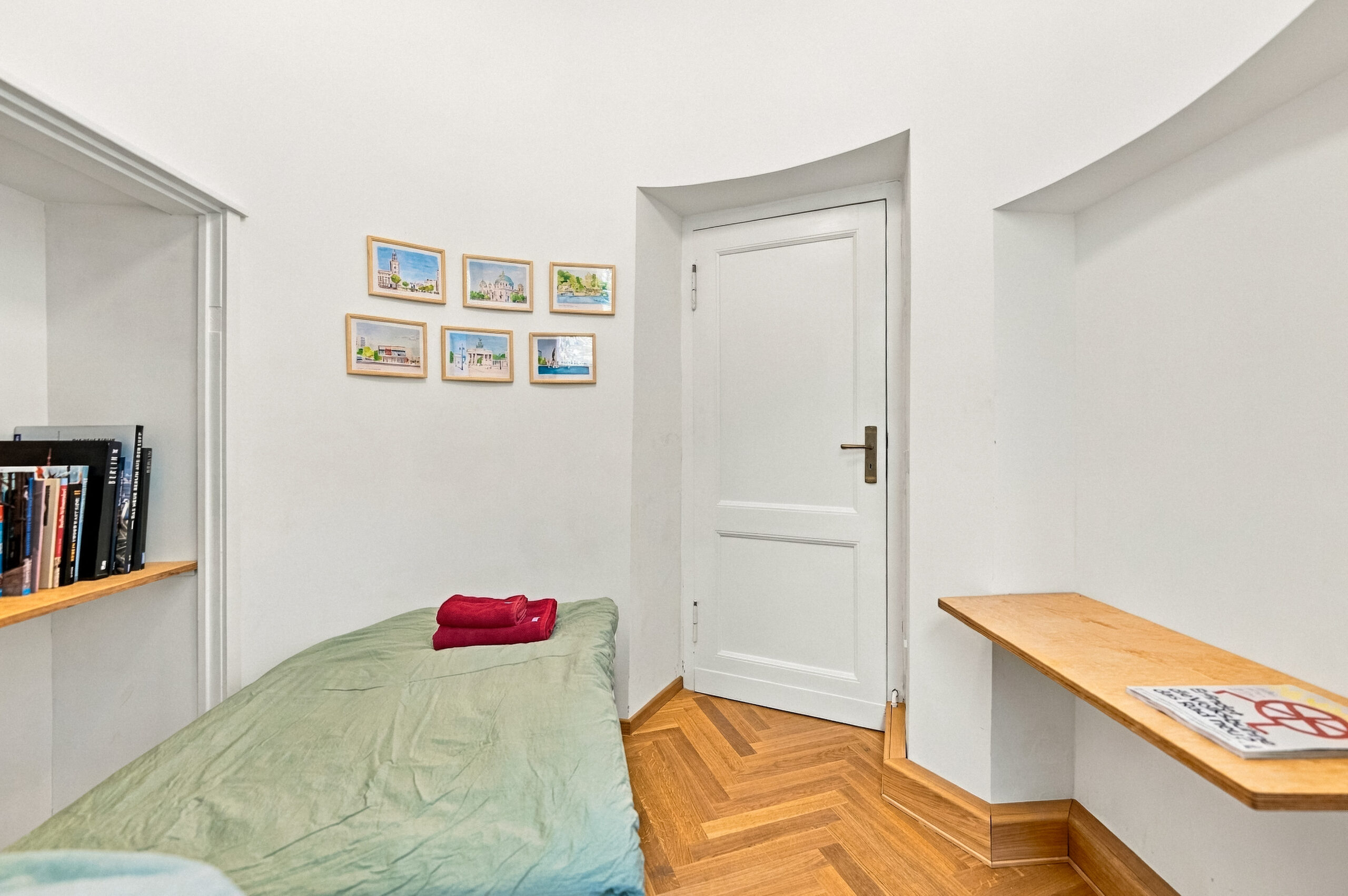Single bed room with framed pictures and shelf
