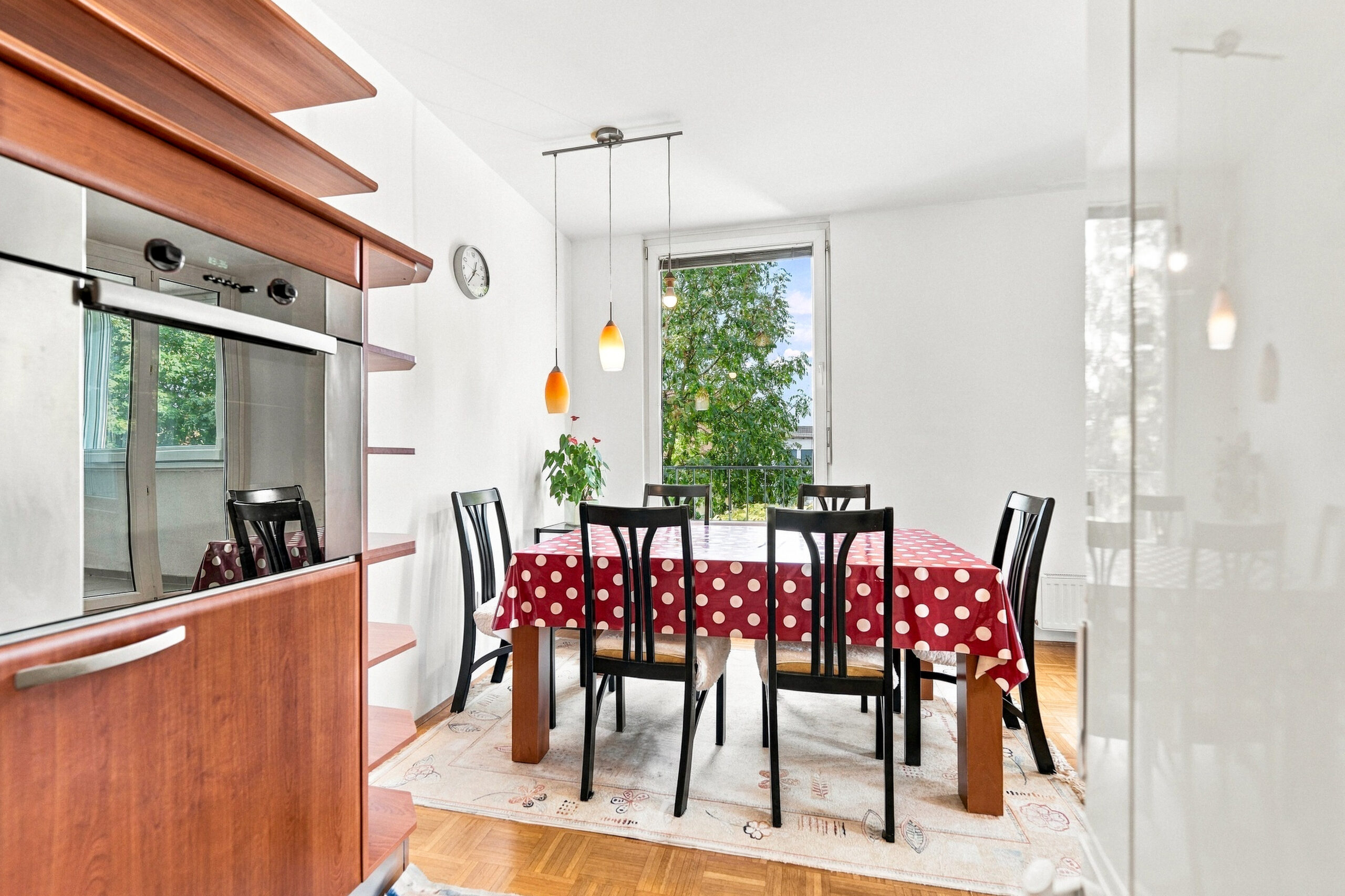 Dining table with red tablecloth near kitchen area