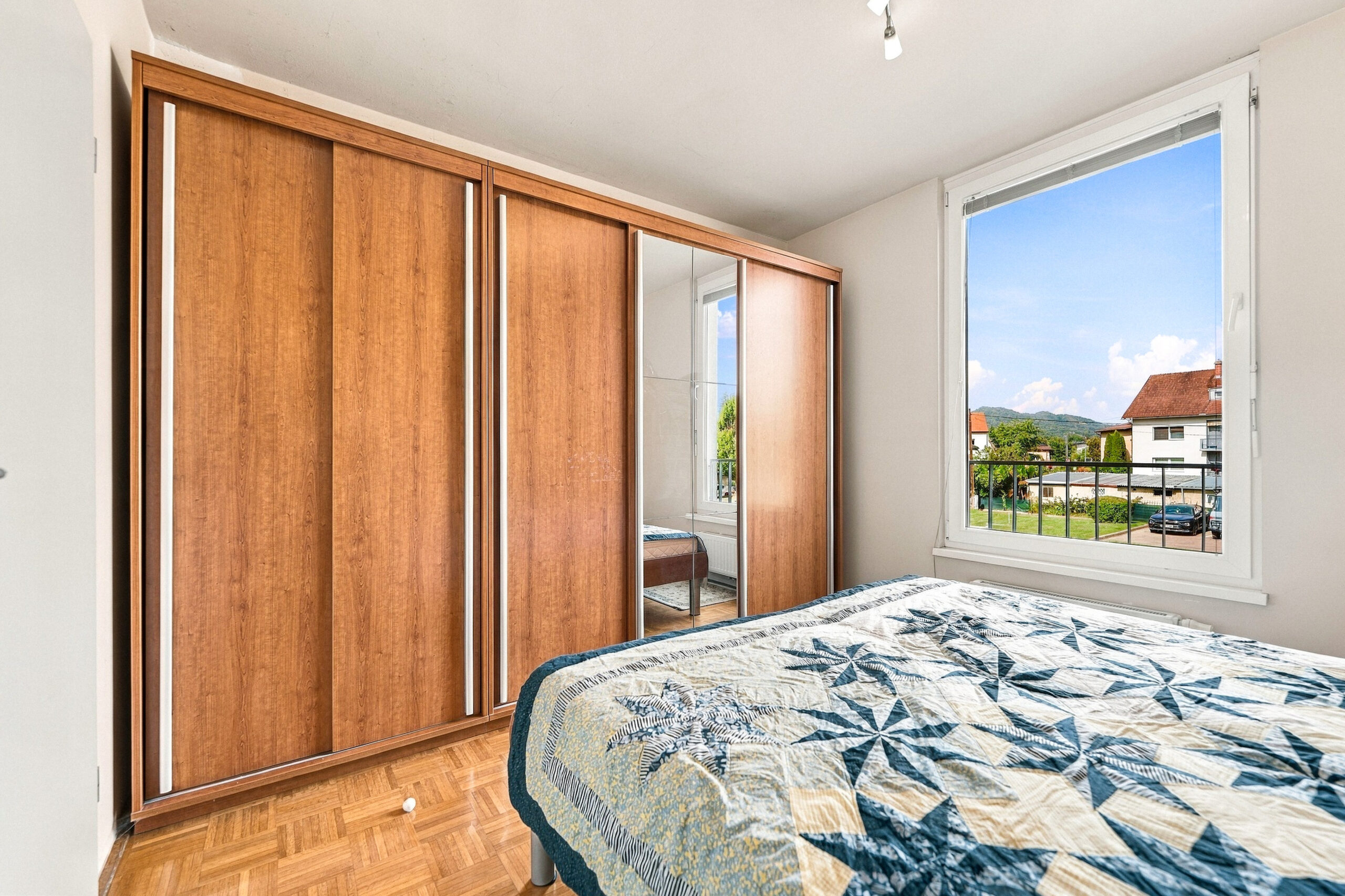 Bedroom with wooden wardrobe and floral bedspread